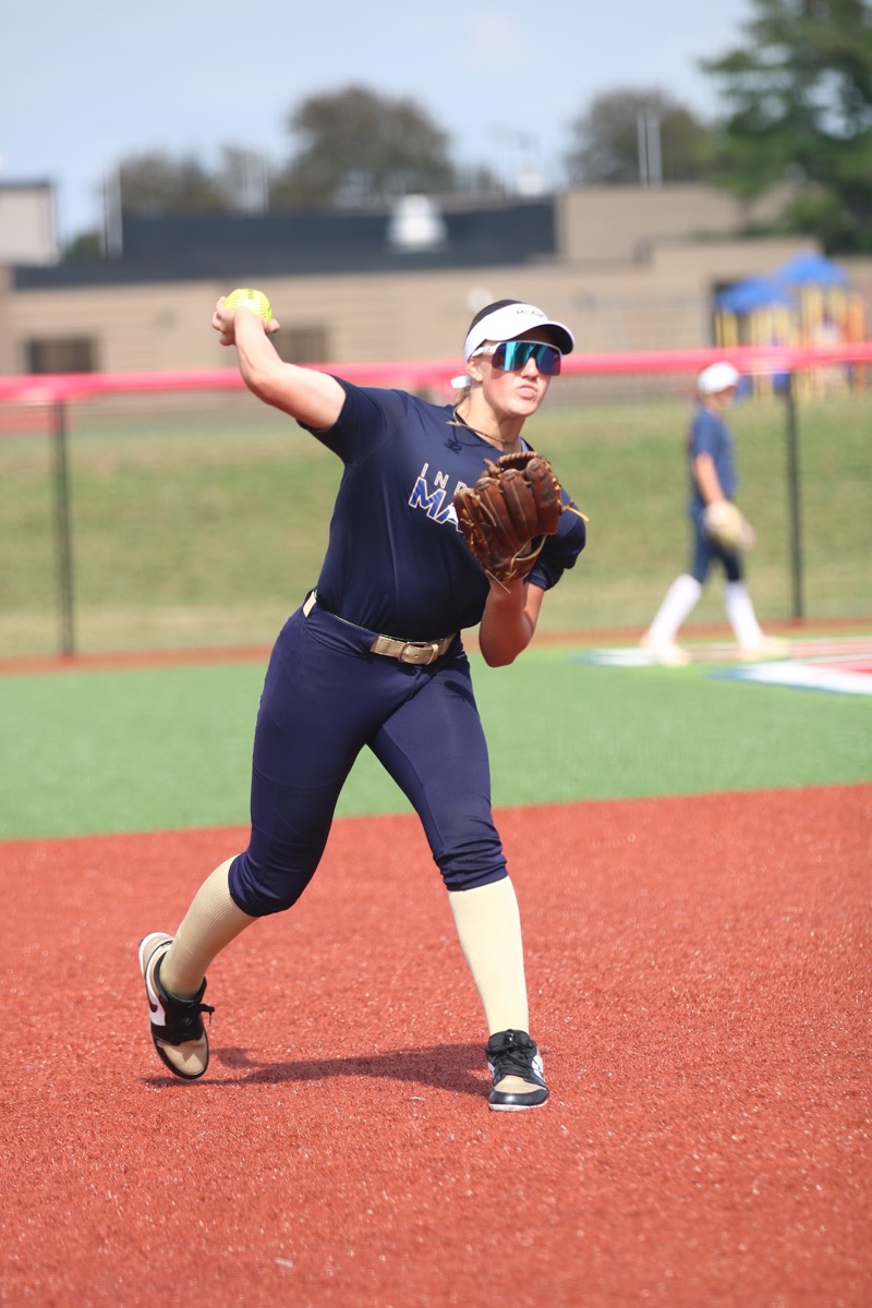 Softball infielder throwing across the diamond during a game