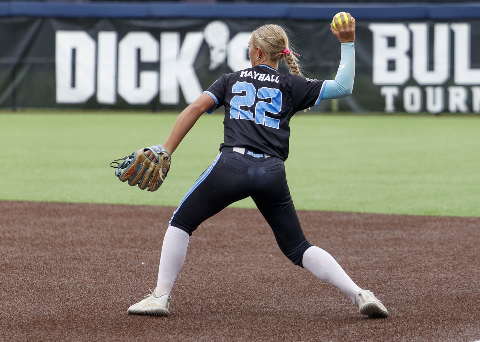 Softball athlete making a high-intent throw during a tournament game