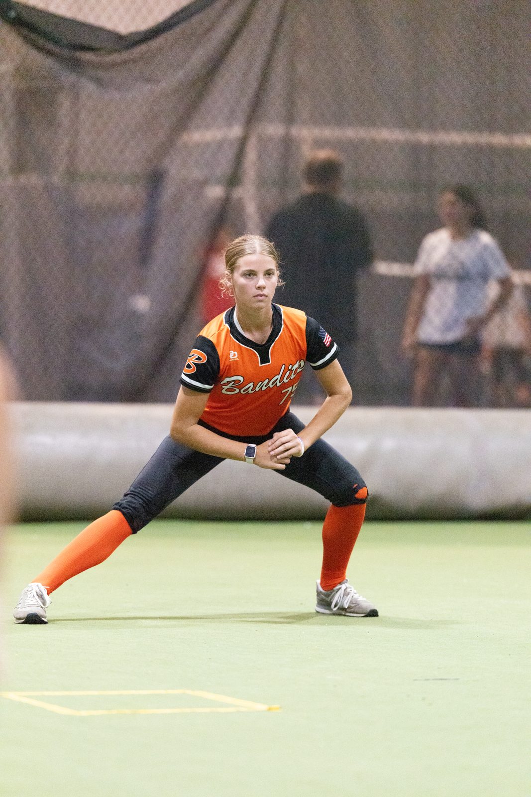 A softball athlete set in her ready position, working alone