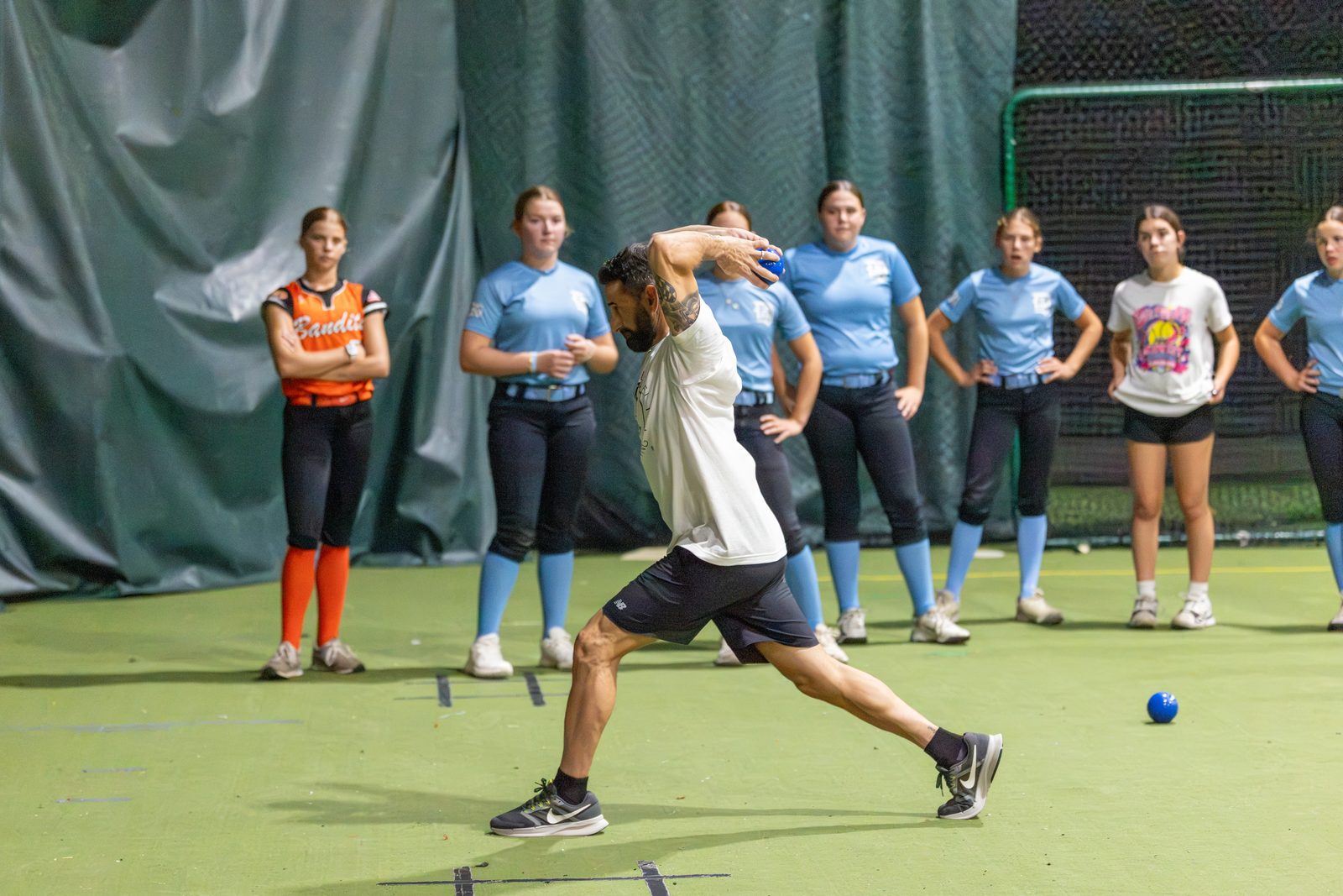 Austin Wasserman demonstrating an overhand throw in front of a group of softball athletes