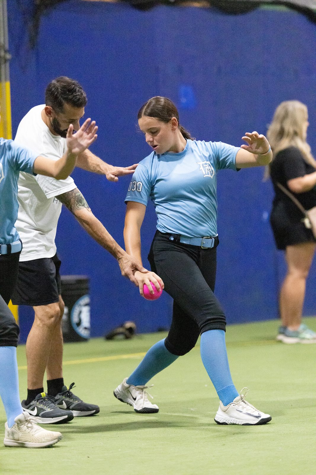Hands-on coaching of an athlete's throwing position with a weighted plyo ball