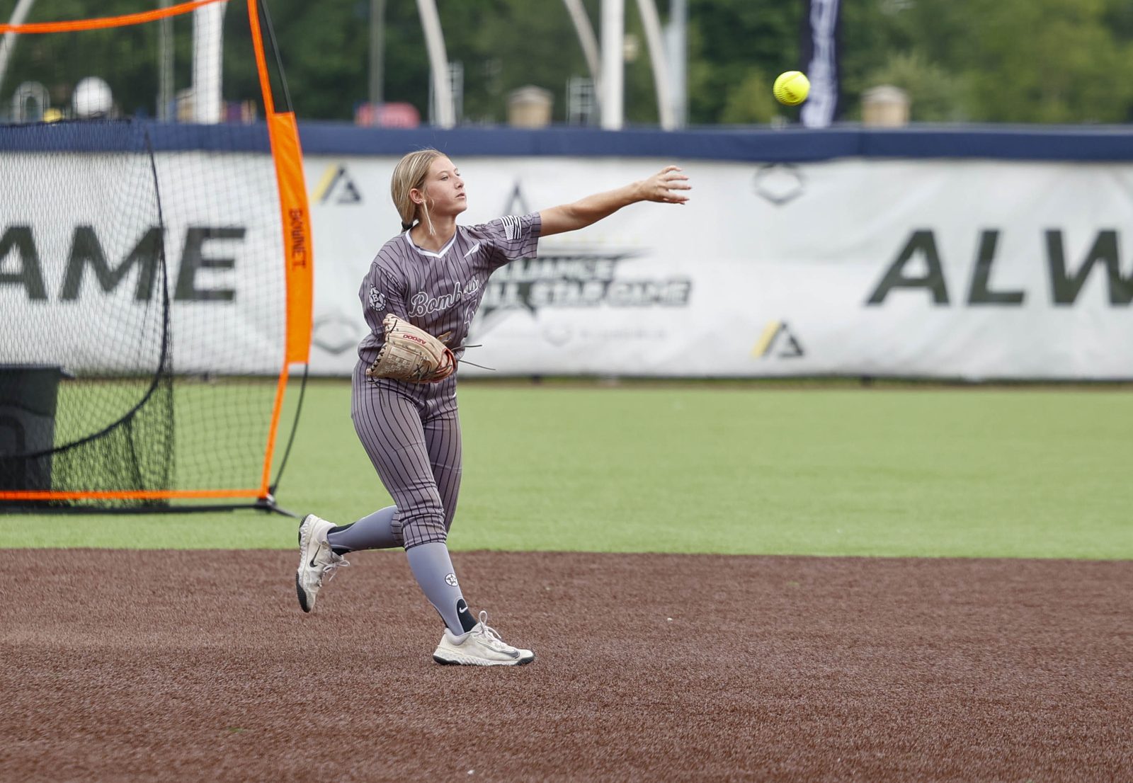 A softball athlete at release, the whole body still moving through the throw
