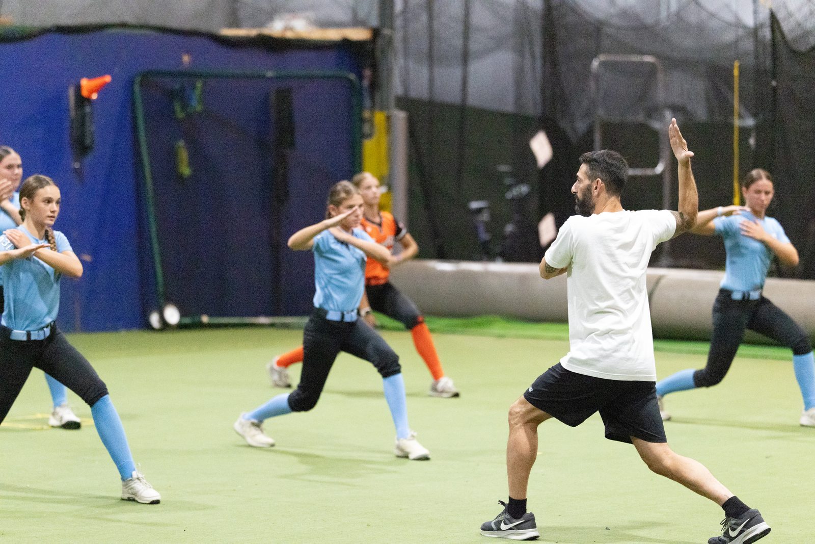 A line of softball athletes working through a movement pattern together at a High Level Throwing clinic