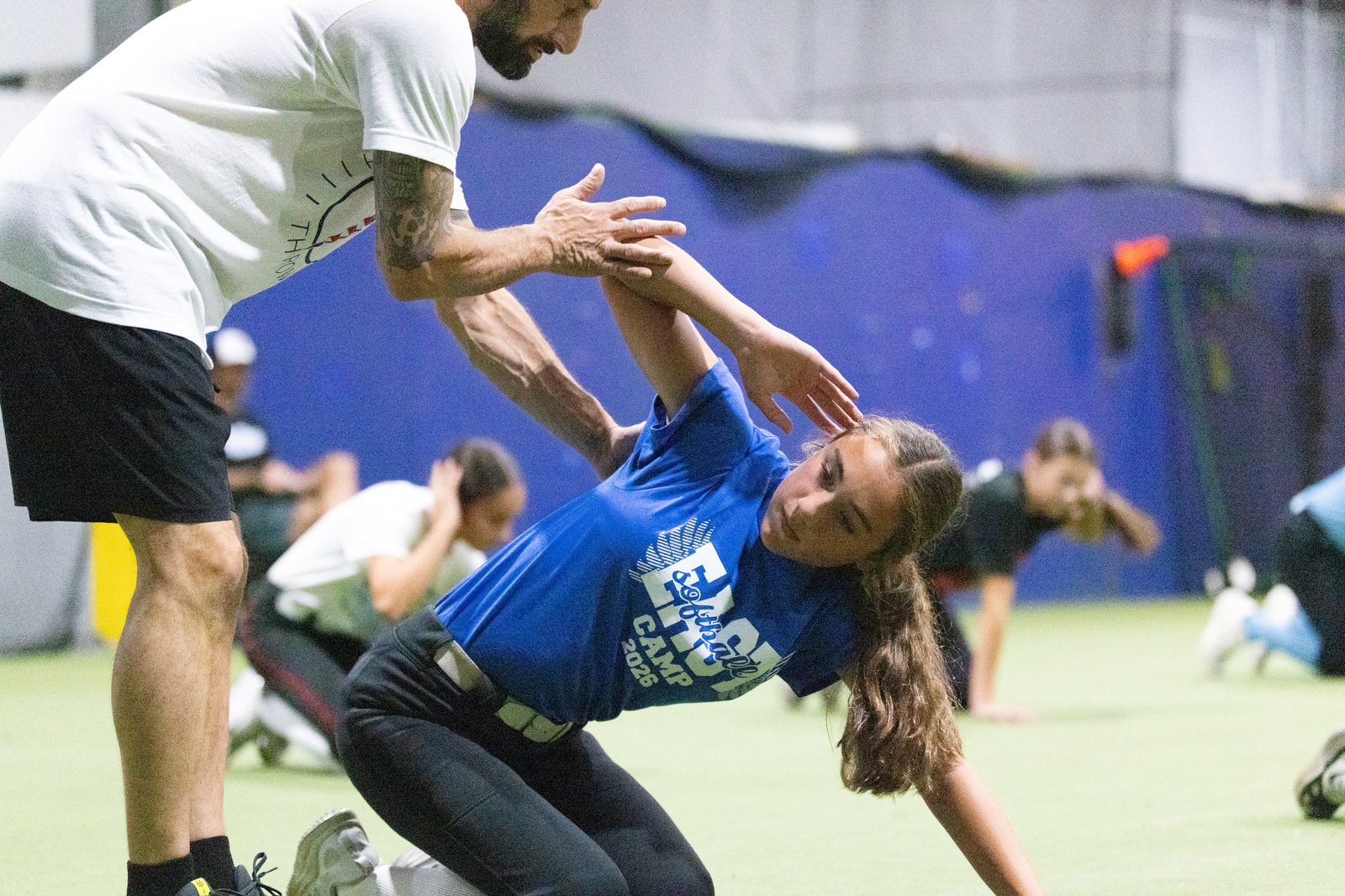 Hands-on coaching of an athlete's arm position and scapular movement during a throwing pattern