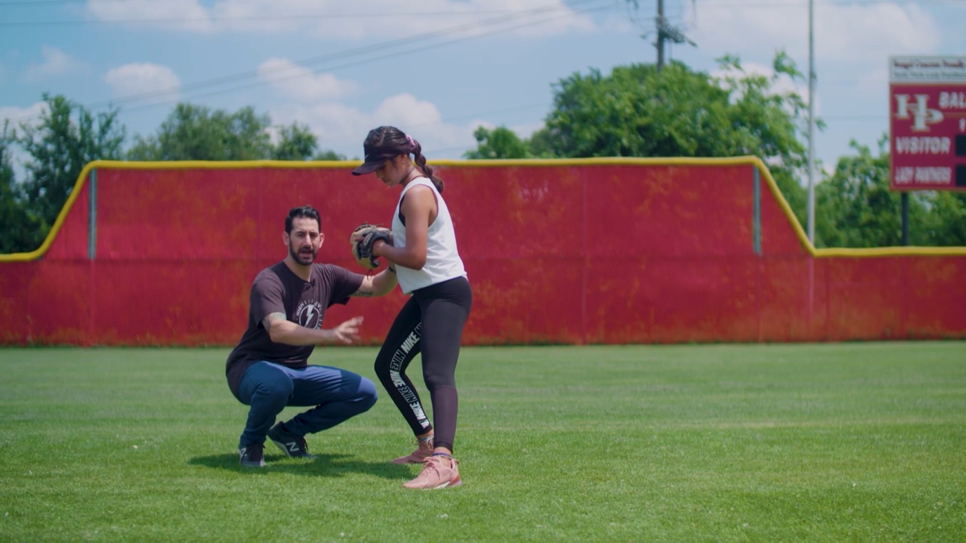 Softball athlete being coached through the overhand throwing pattern